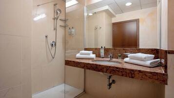 Une salle de bain moderne avec une douche à parois de verre, un comptoir en marbre et un grand miroir.