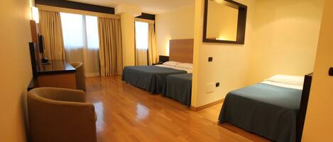 A hotel room with two single beds, a desk, a chair, and a large mirror.