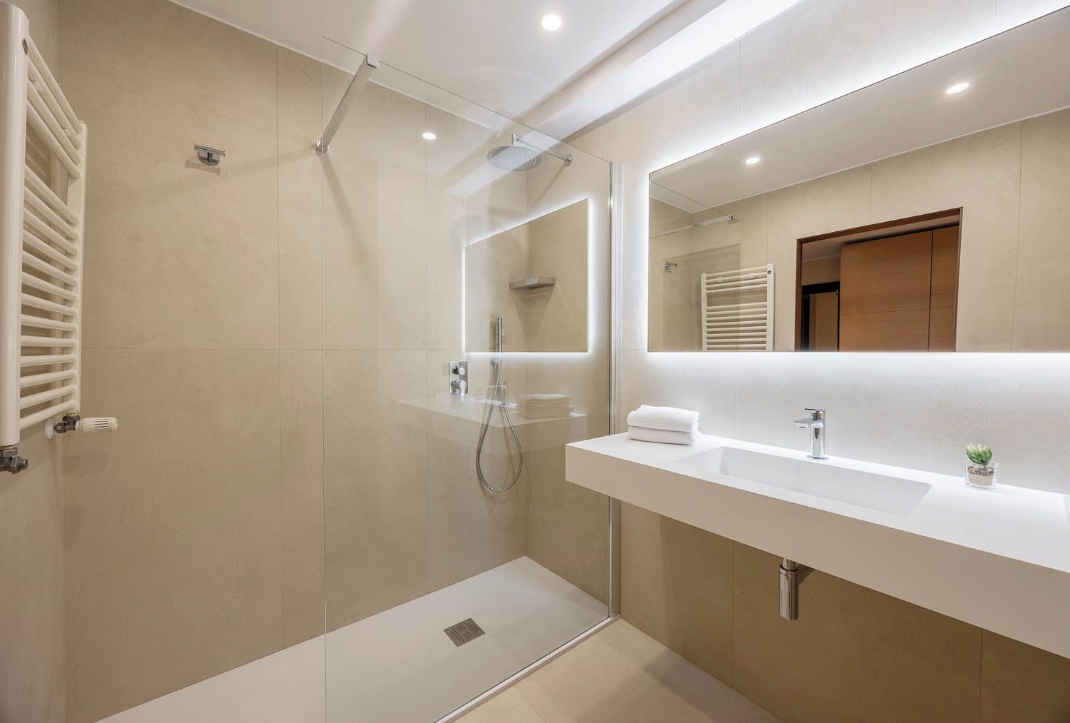 Un bagno moderno con doccia vetro, mobile lavabo bianco e porta asciugamani.