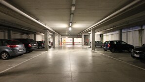 A multi-level parking garage with concrete floors and columns, featuring several parked cars. - Golf Hotel Milano (Opera)