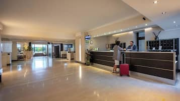 A hotel reception area with a reception desk, a clock, and a reception sign.