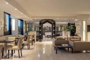Amplia sala de estar con mesa y sillas de comedor, un conjunto de sofás y una cocina al fondo.