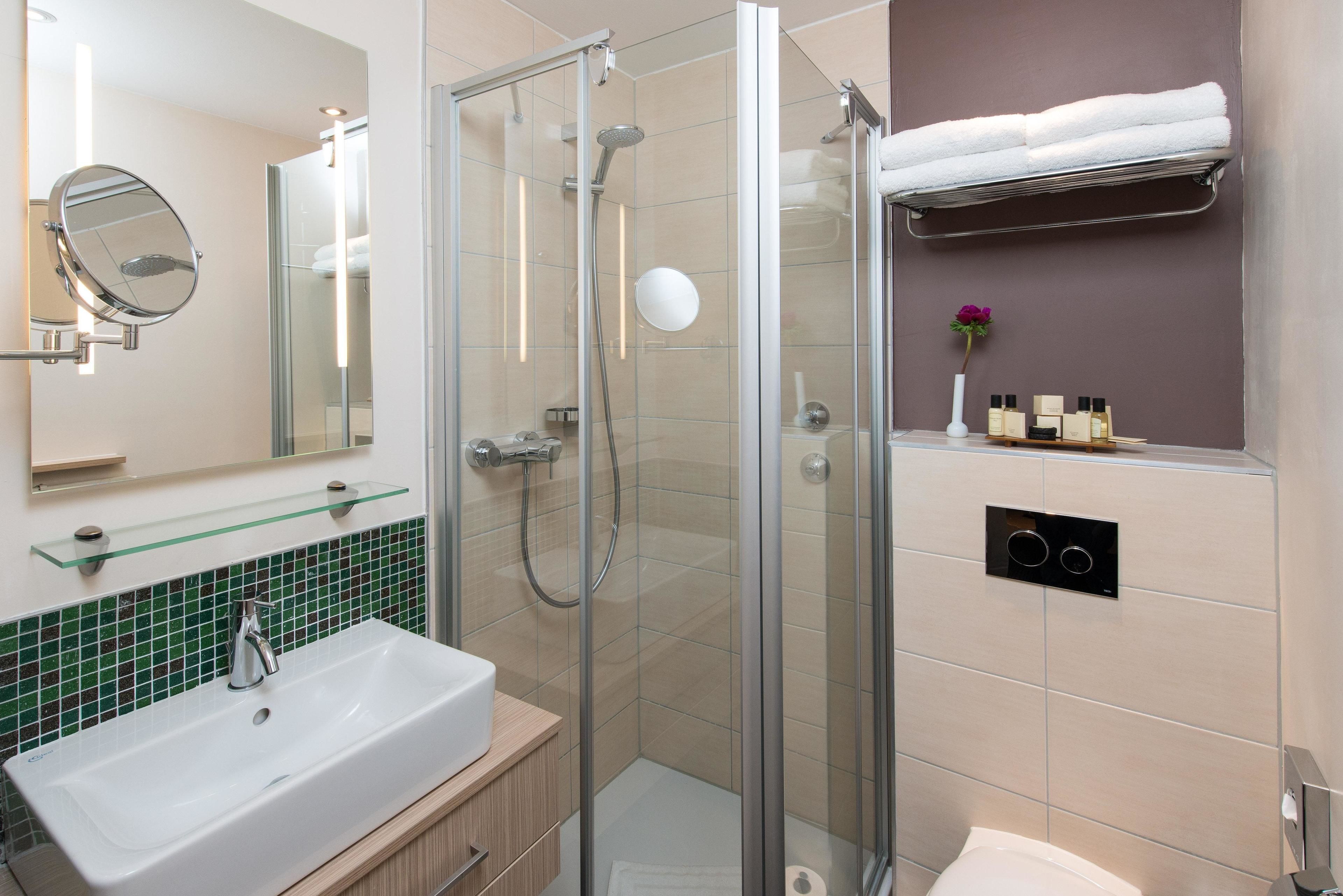 A modern bathroom with a glass-enclosed shower, a white sink, and a mirror.