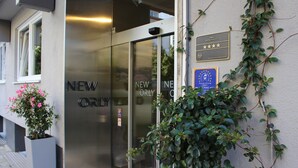 A hotel entrance with a glass door, a plaque indicating a 4-star rating, and a sign for 'NEW ORLY'. - New Orly (Munich)