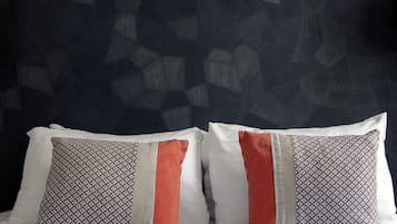 A bed with striped bedding and two pillows with geometric patterns and a red accent.