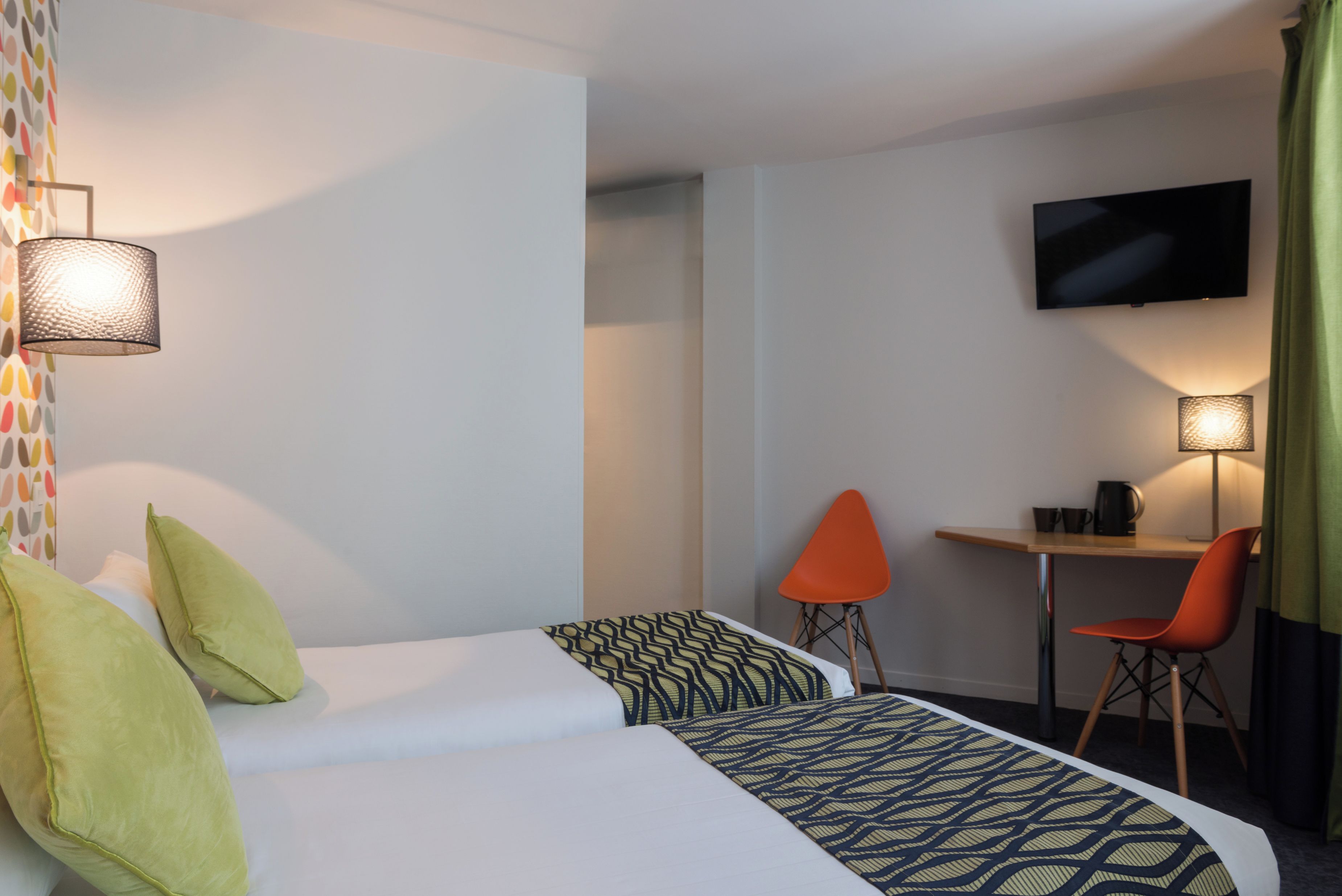 Una habitación de hotel con una cama, un escritorio, dos sillas, un televisor y una lámpara.