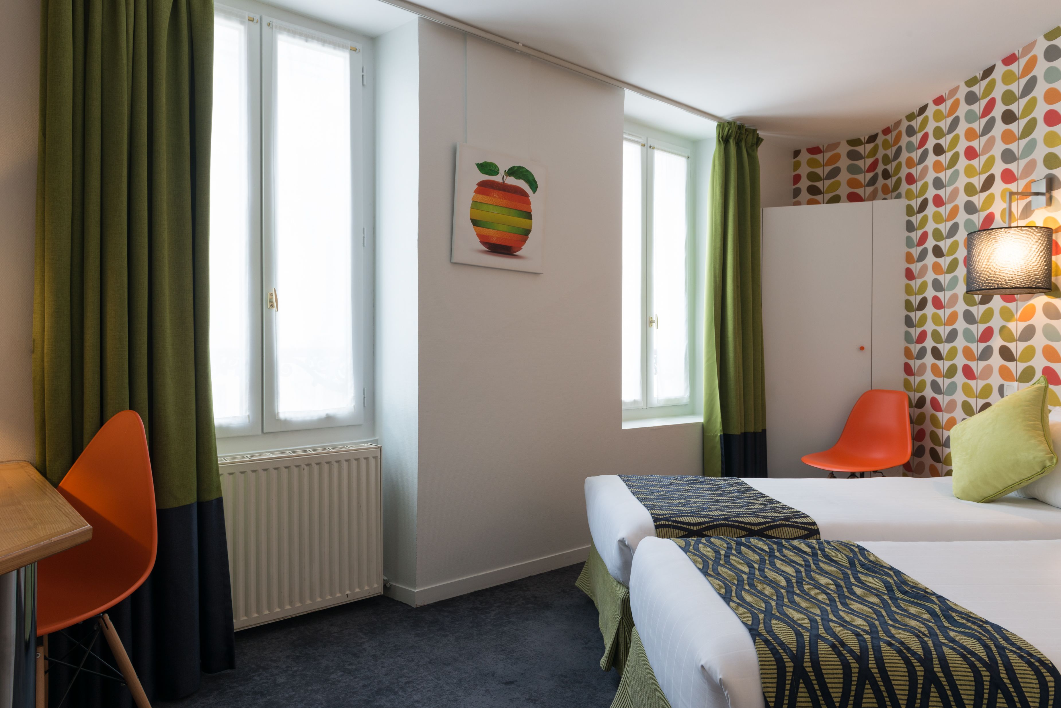 Habitación de hotel con dos camas, un escritorio, una silla y un radiador.