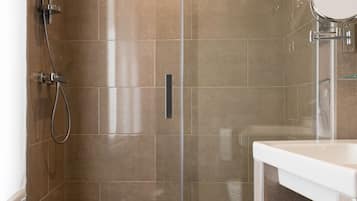 Ein modernes Badezimmer mit einer gläsernen Duschkabine, einem weißen Waschbecken und einem Handtuchhalter.