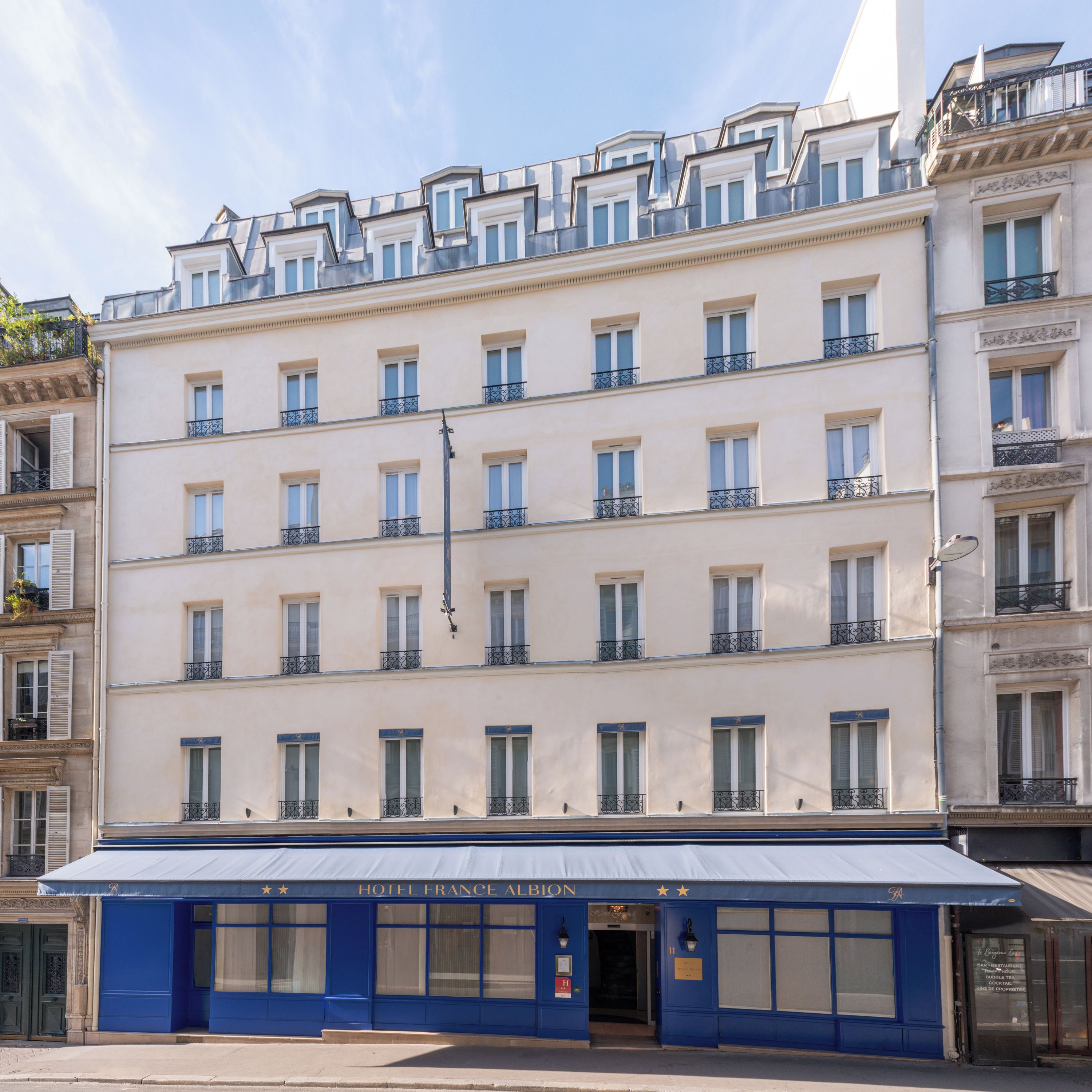 A multi-story hotel with a blue facade, multiple balconies, and a sign indicating it is the Hotel France Albion.