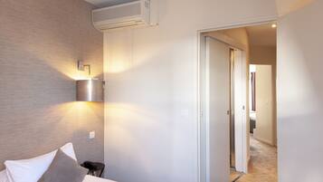 Una habitación de hotel con cama, mesita de noche, lámpara de pared y equipo de aire acondicionado.