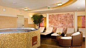 A spa area with a hot tub, lounge chairs, and a tiled floor. - Hotel Kalvaria (Gyor)