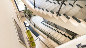A multi-level interior with a staircase, seating areas, and a potted plant. - Hotel Kalvaria (Gyor)