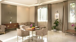 A modern living room with a sofa set, a dining table with chairs, a wooden cabinet, and a potted plant. - Hotel Kalvaria (Gyor)