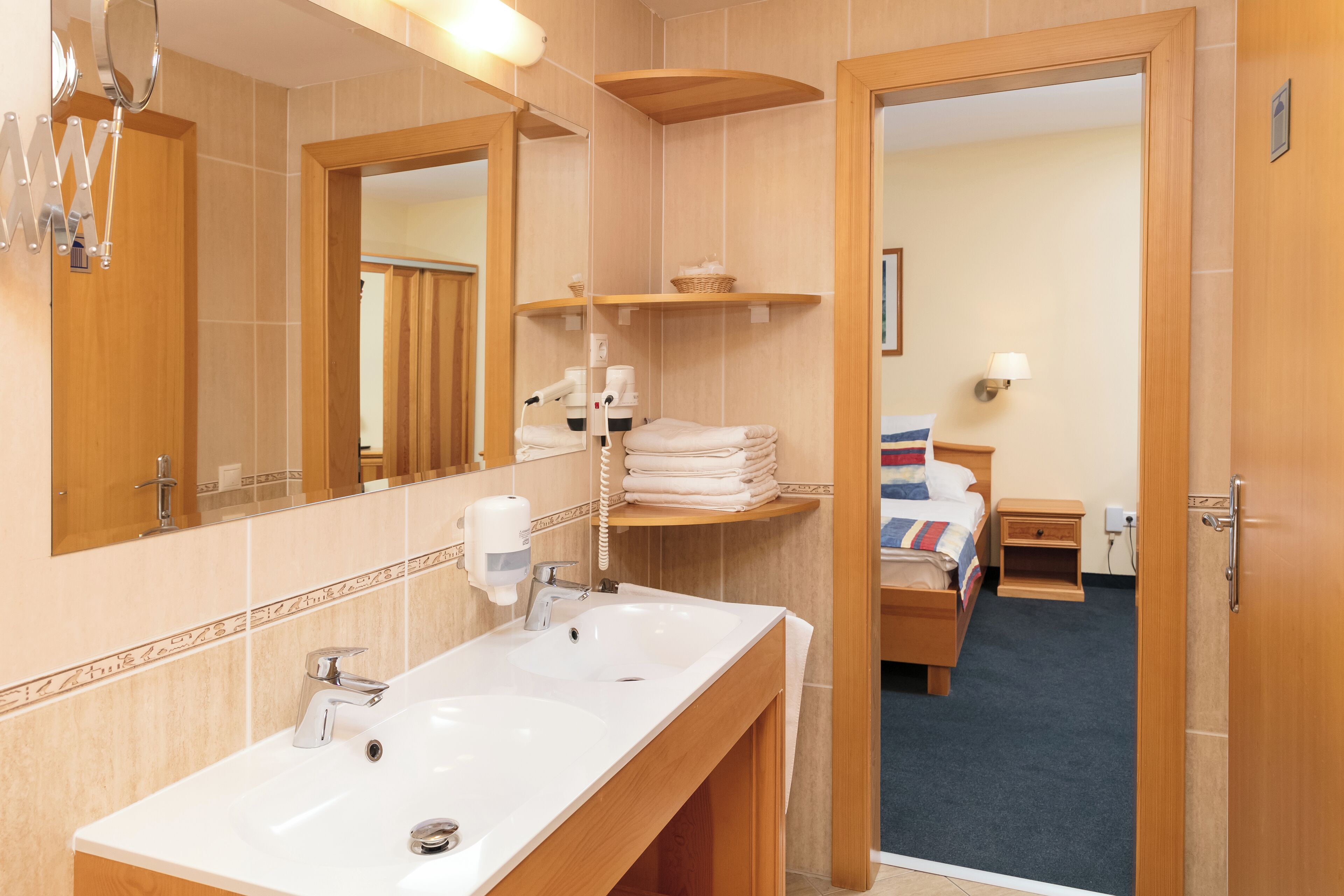 Une salle de bain d’hôtel avec un grand lavabo, un miroir et un porte-serviettes.