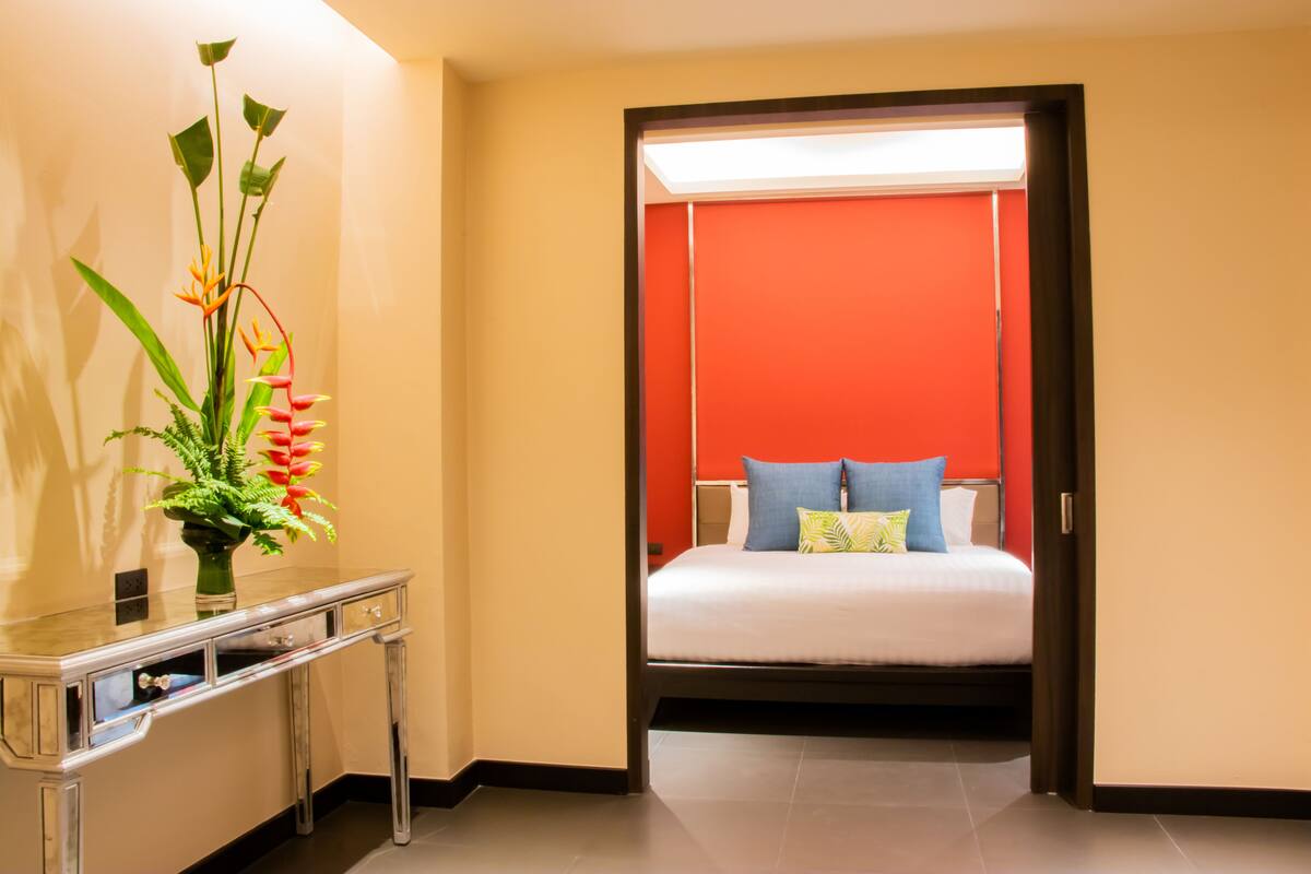 A hotel room with a bed, a nightstand, and a vase with flowers.