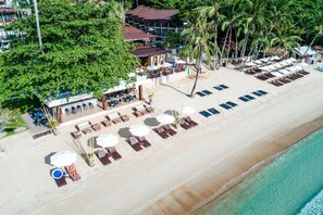 Na praia, areia branca, espreguiçadeiras, guarda-sóis 