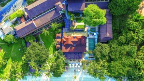 Vista aérea de un resort con playa, palmeras y un área de piscina.