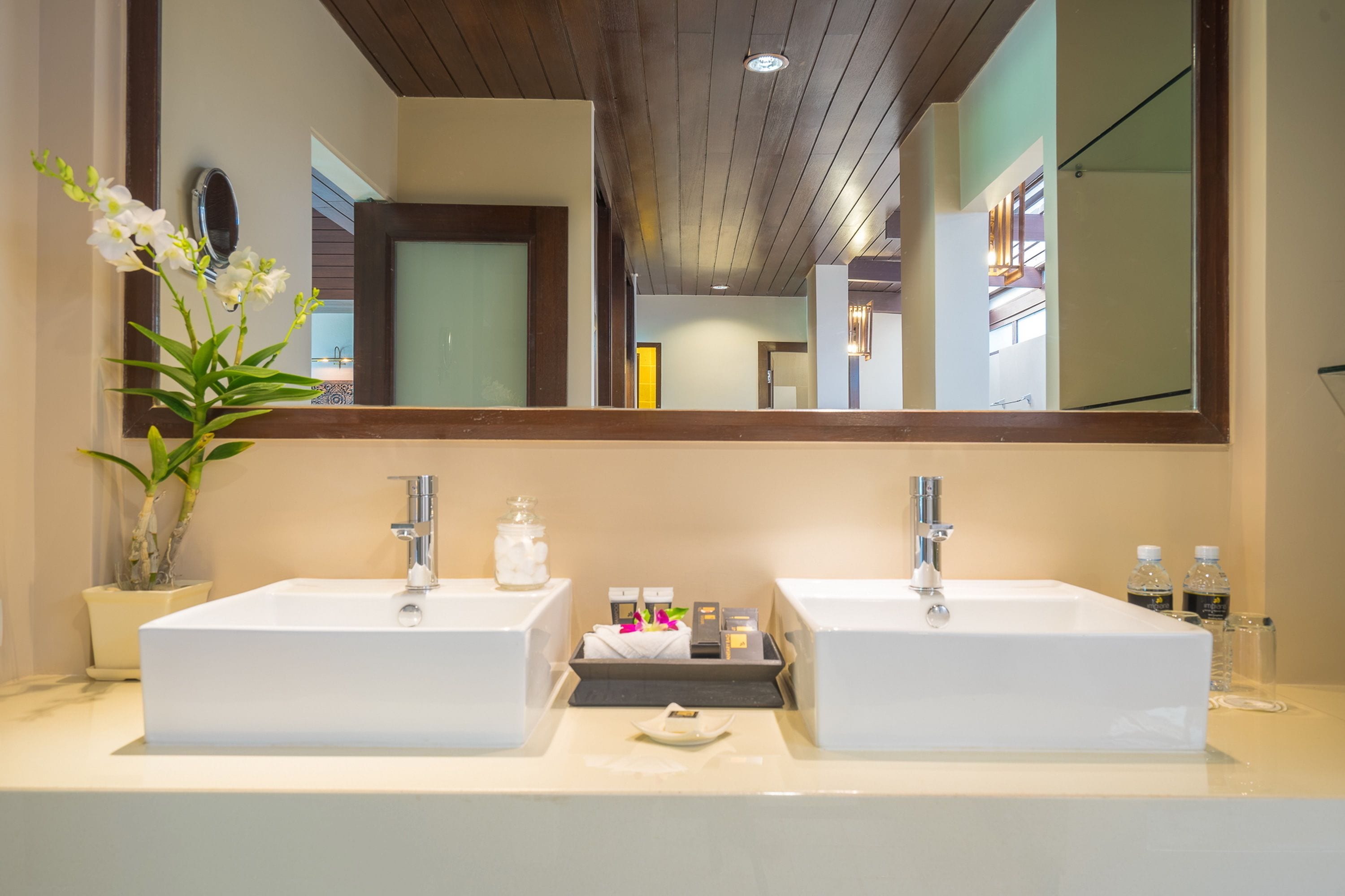 Un baño con dos lavamanos, un espejo grande y una orquídea en maceta.