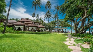 Un resort con varias construcciones tipo bungalow, un césped cuidado y una vista despejada del océano.