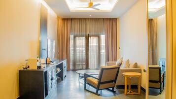 Une chambre d’hôtel moderne dotée d’un coin salon, d’un bureau et d’une grande fenêtre avec des rideaux.