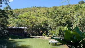 A serene outdoor area with a pond, a wooden dock, and lush greenery. - Rio Perlas Thermal Resort & Spa (Dulce Nombre)