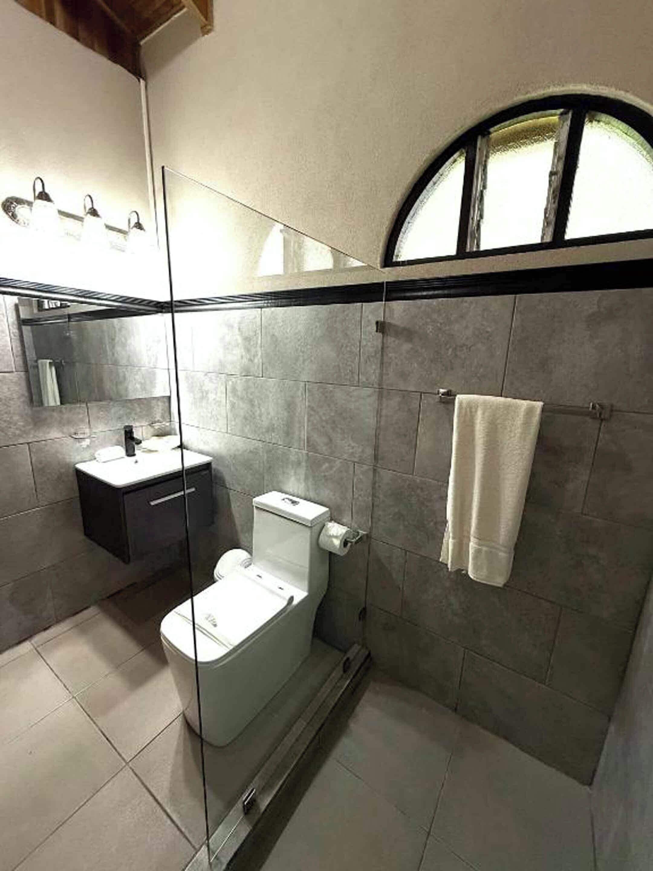 A modern bathroom with a glass shower enclosure, a toilet, and a sink.