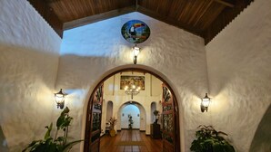 An arched entrance with tiled flooring, wall-mounted lamps, and potted plants. - Rio Perlas Thermal Resort & Spa (Dulce Nombre)