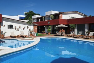 Una piscina con sillones de descanso y un área de patio.