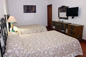 Une chambre avec deux lits, une commode, un téléviseur et une lampe.
