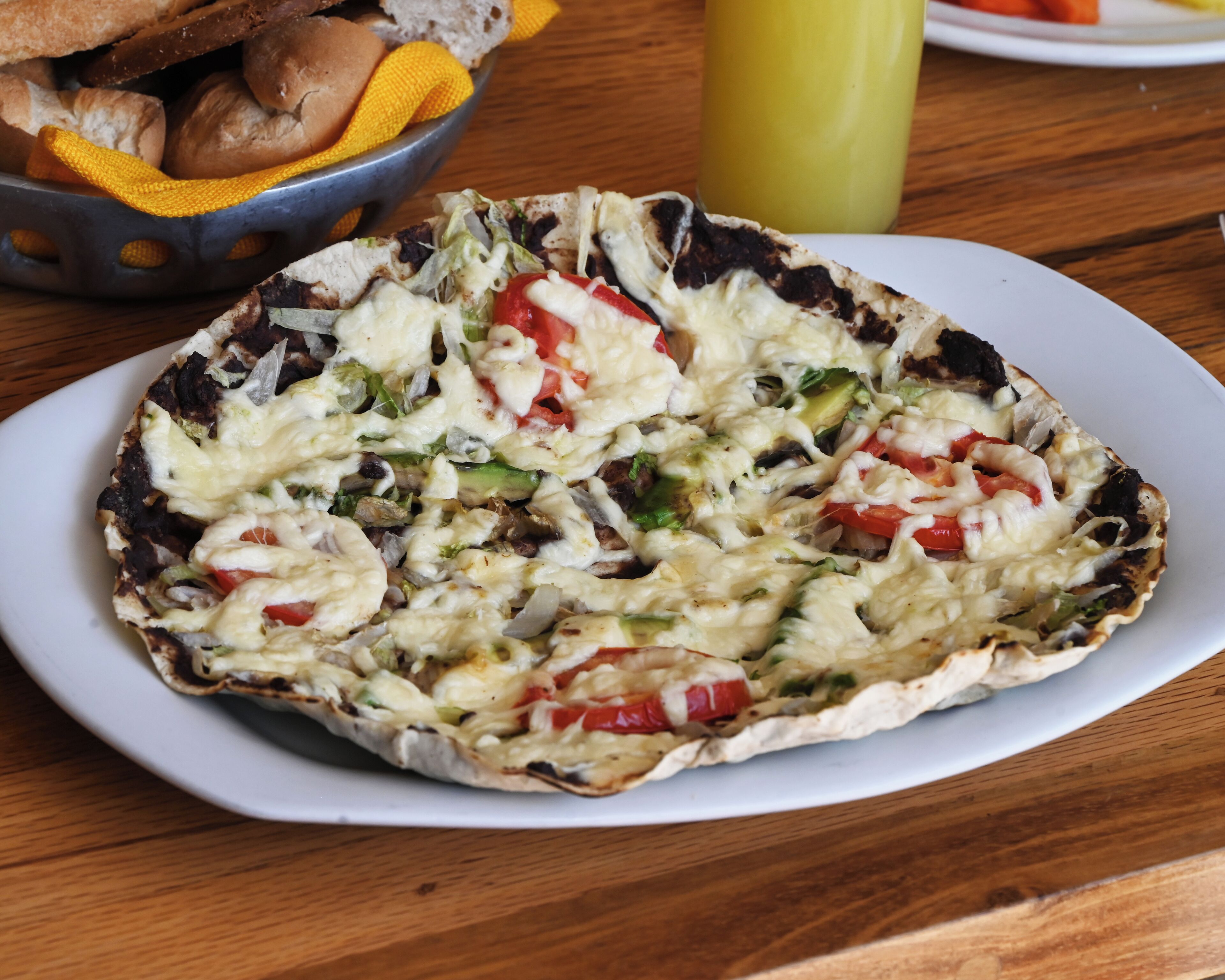 A pizza on a white plate with a wooden table background.