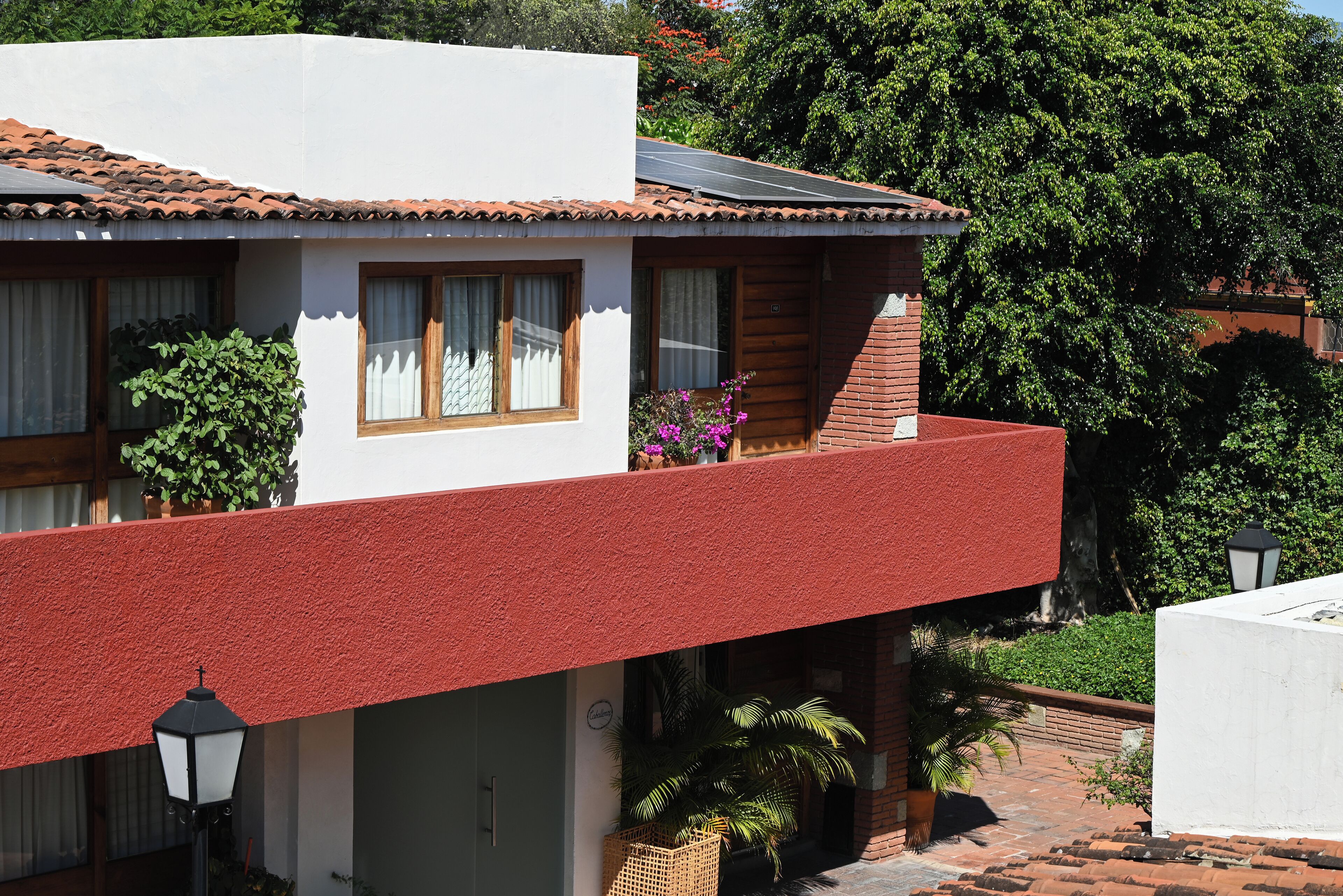 A two-story building with a red balcony, white walls, and a tiled roof.