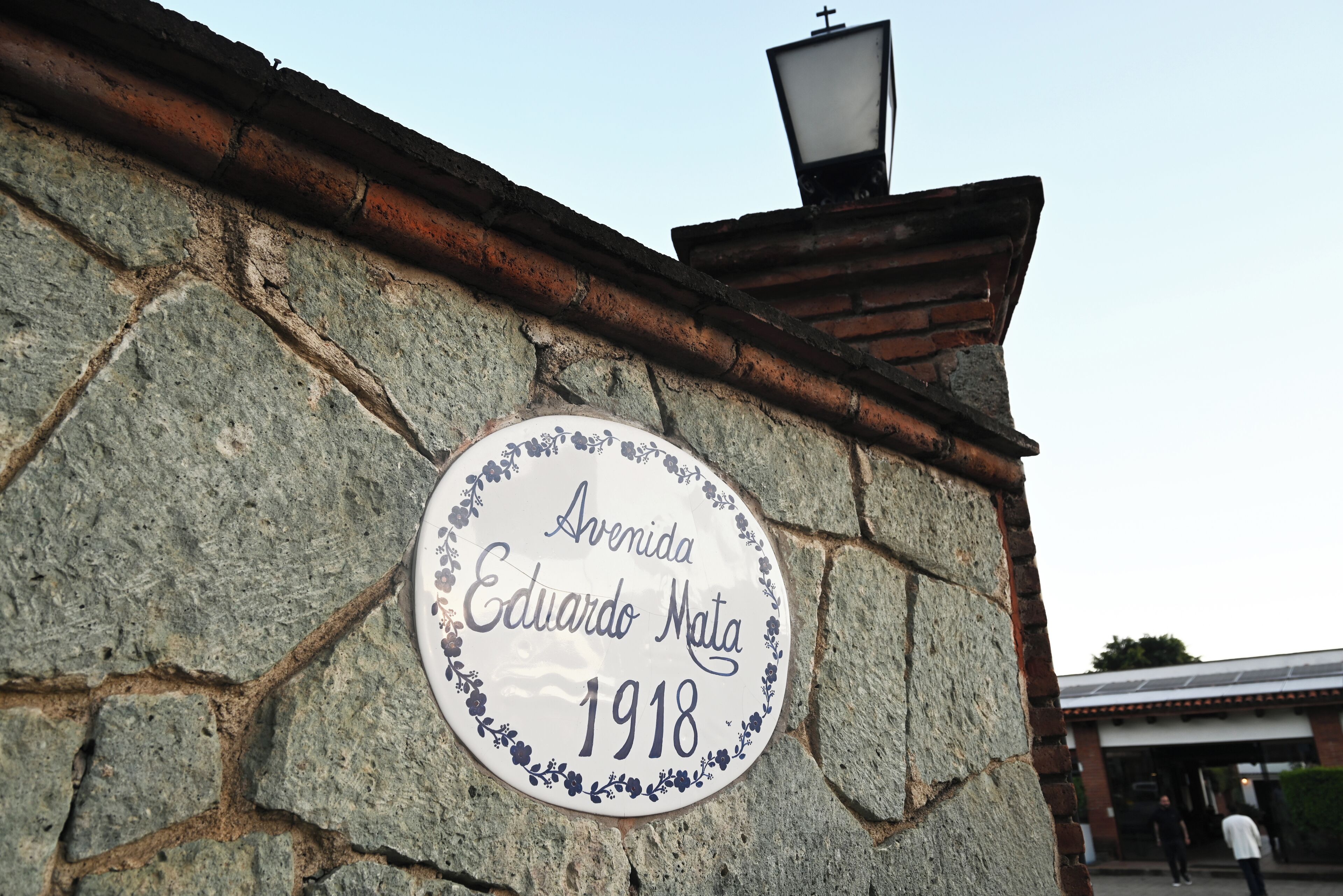 A stone wall with a plaque reading "Avenida Eduardo Mata 1918".