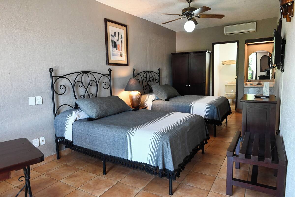 A bedroom with two beds, a ceiling fan, a bedside table, and a wardrobe.