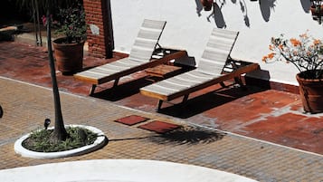 Un área de piscina con sillones reclinables y plantas en macetas.
