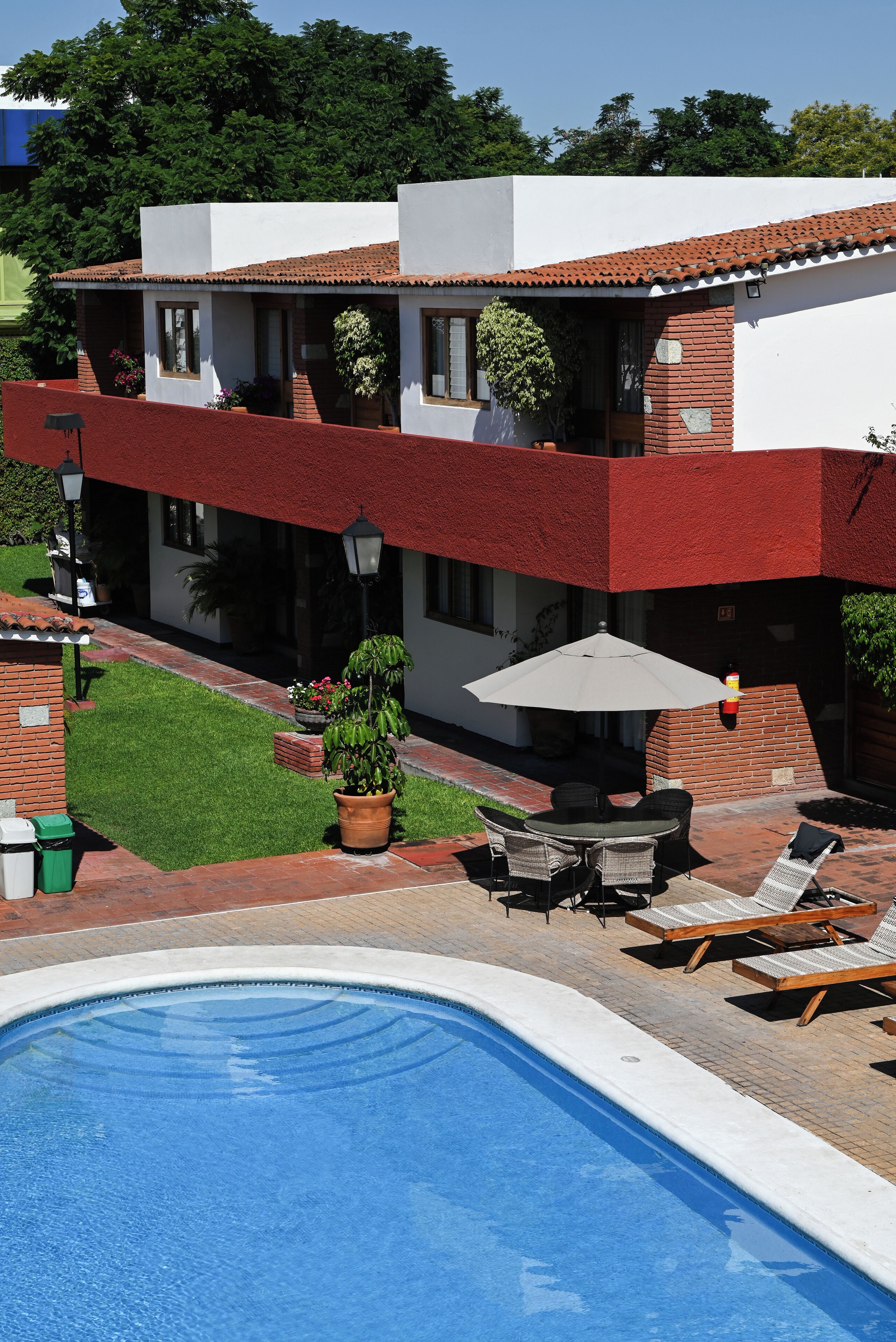 Una casa moderna con piscina, mobiliario de exterior y un jardín bien cuidado.