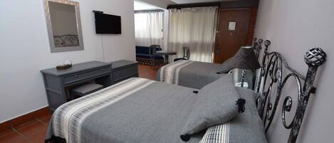 A bedroom with two beds, a desk, a chair, and a television.