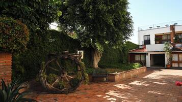 A courtyard with a large water wheel, brick pathway, and a modern building with a balcony.