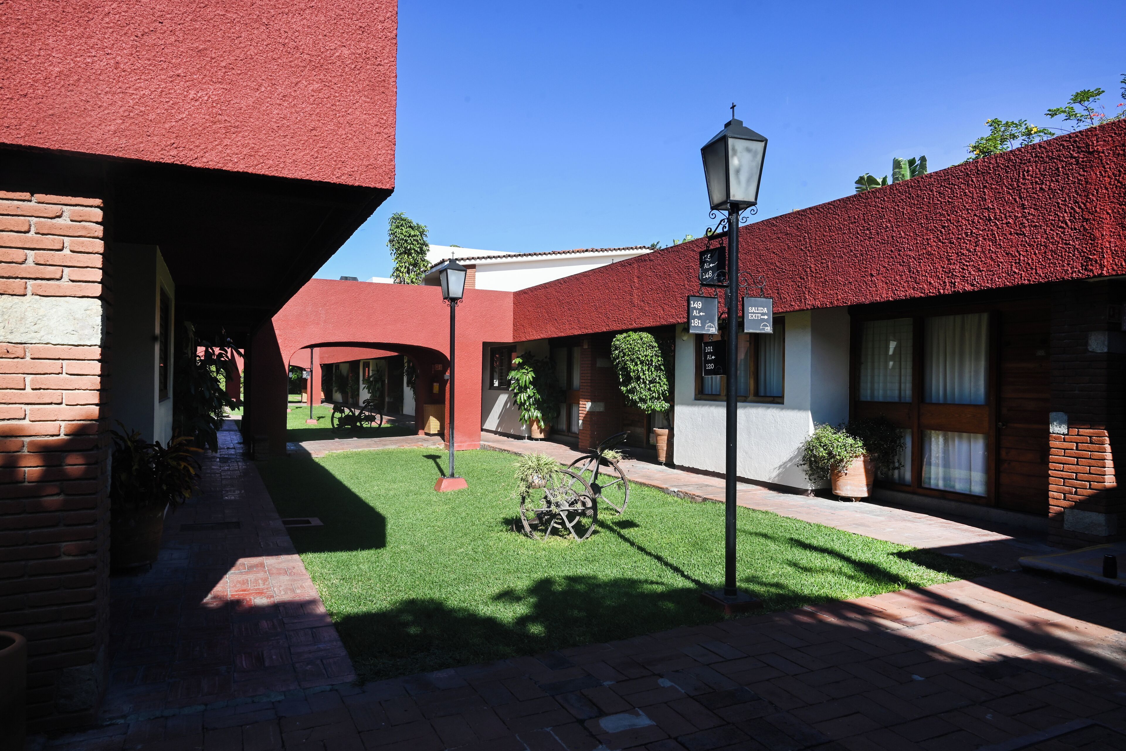 A courtyard with red-tiled buildings, a brick pathway, and potted plants.