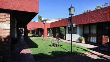 A courtyard with red-tiled buildings, a brick pathway, and potted plants.