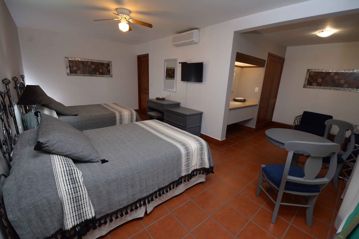 A bedroom with two beds, a desk, a chair, and a ceiling fan.