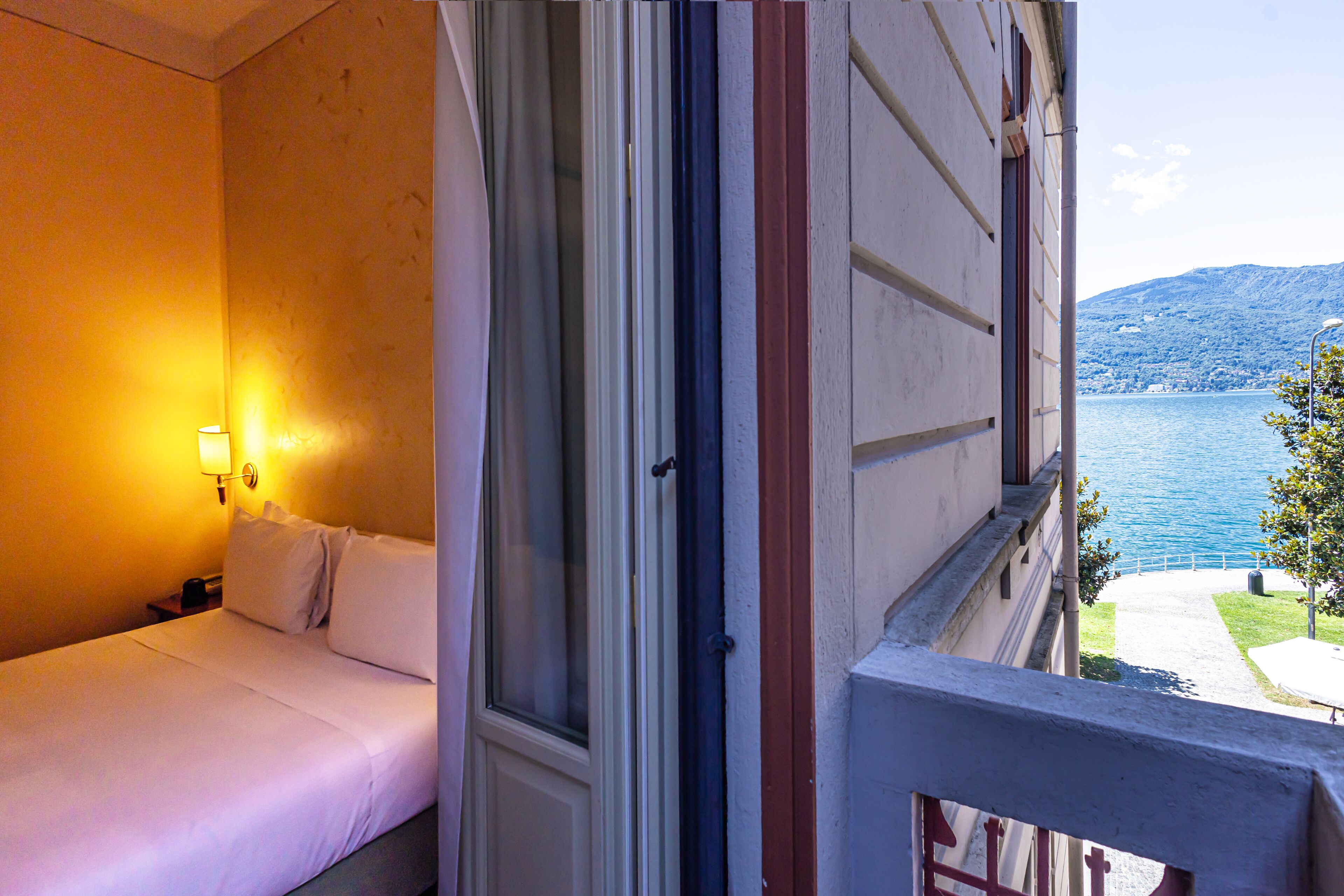 Habitación de hotel con una cama, una mesita de noche, una lámpara y vistas a un lago.