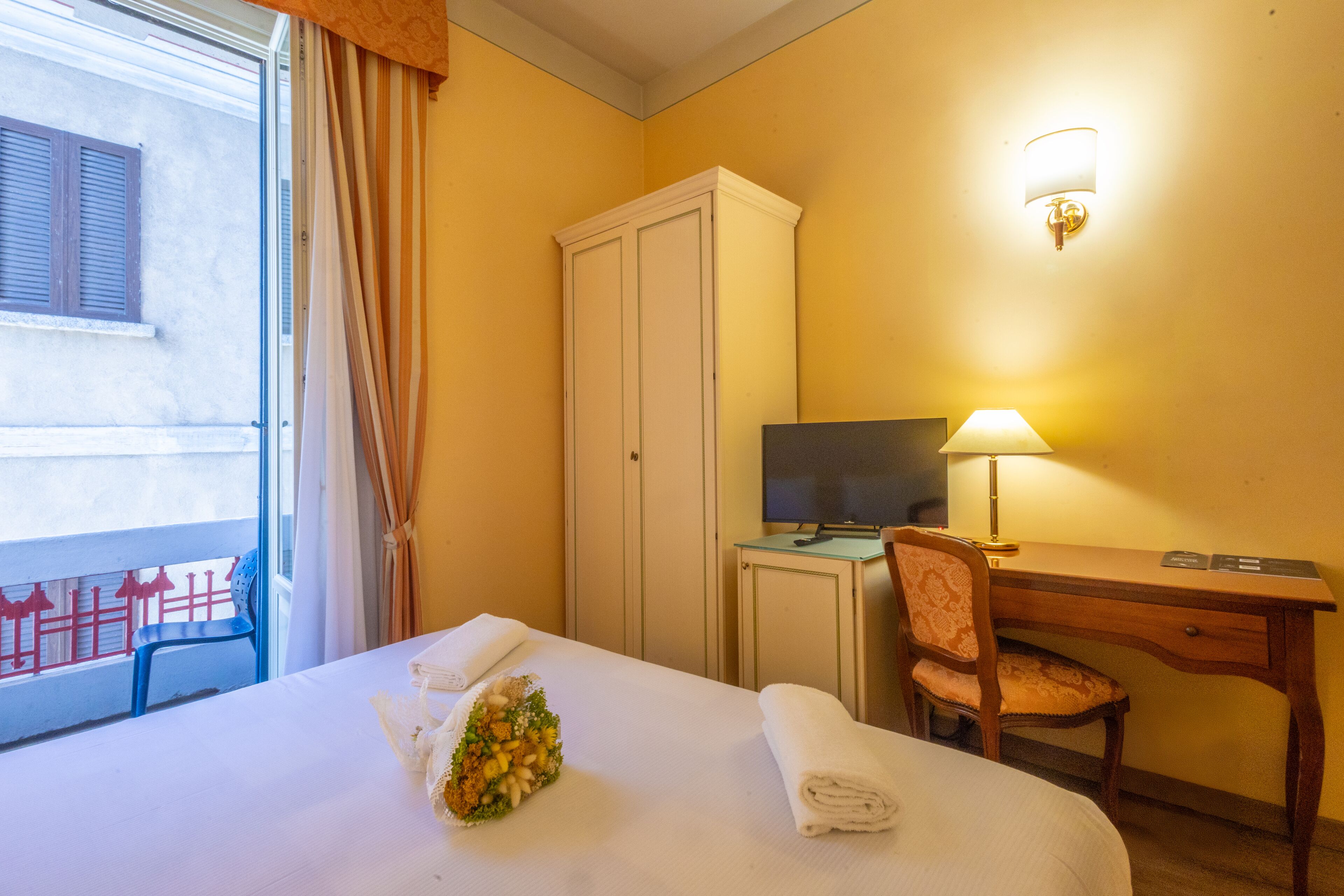 Une chambre d’hôtel équipée d’un lit, d’un bureau, d’une chaise, d’une armoire et d’un téléviseur.