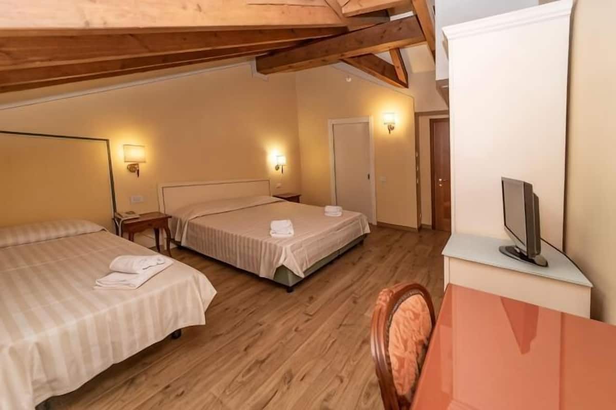 A room with two beds, a television, and a desk.