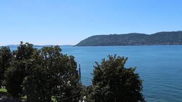 A view of a lake with a distant mountain range and trees in the foreground.