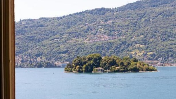 Vista de un lago con una pequeña isla y un paisaje montañoso al fondo.