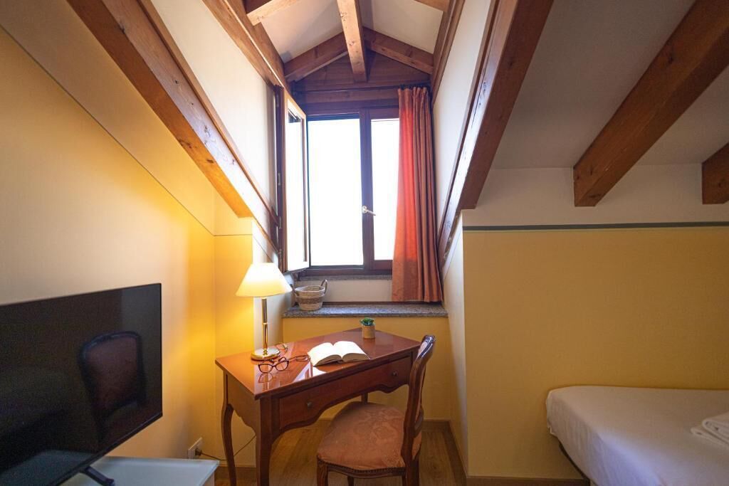 Una stanza accogliente e piccola, con una scrivania, una sedia e un letto.