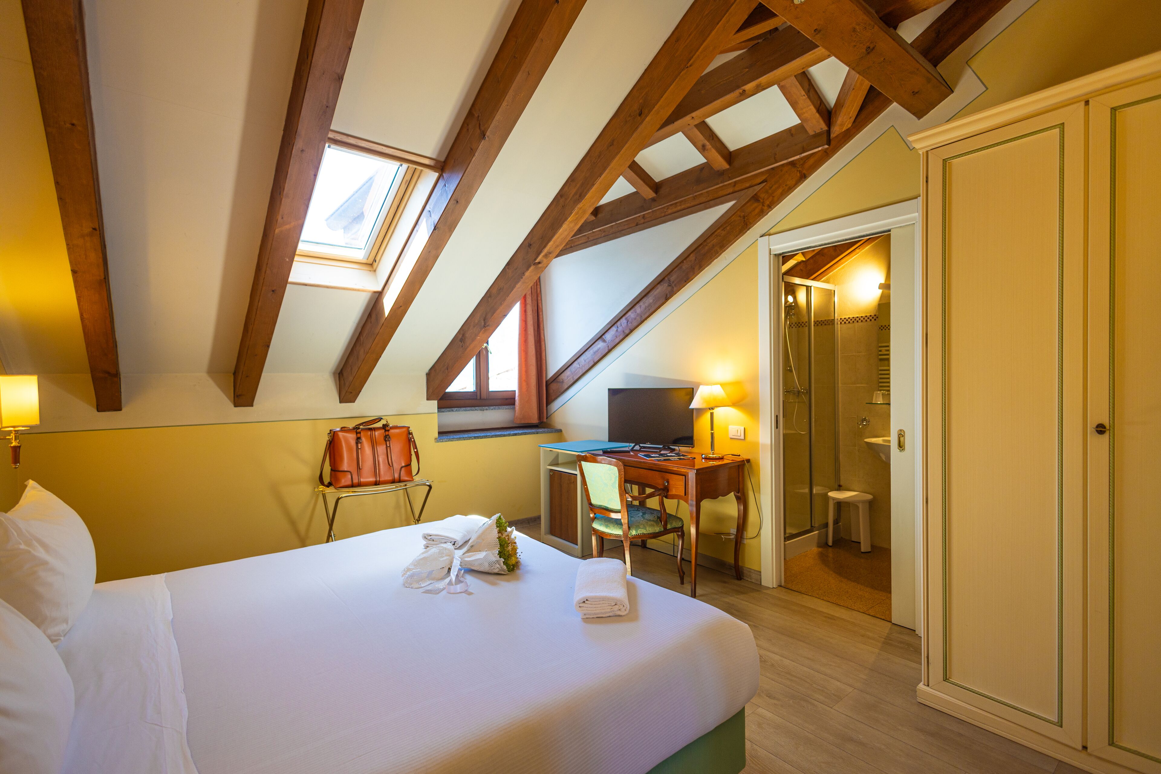 Una habitación de hotel con cama, escritorio, silla, televisor y baño.