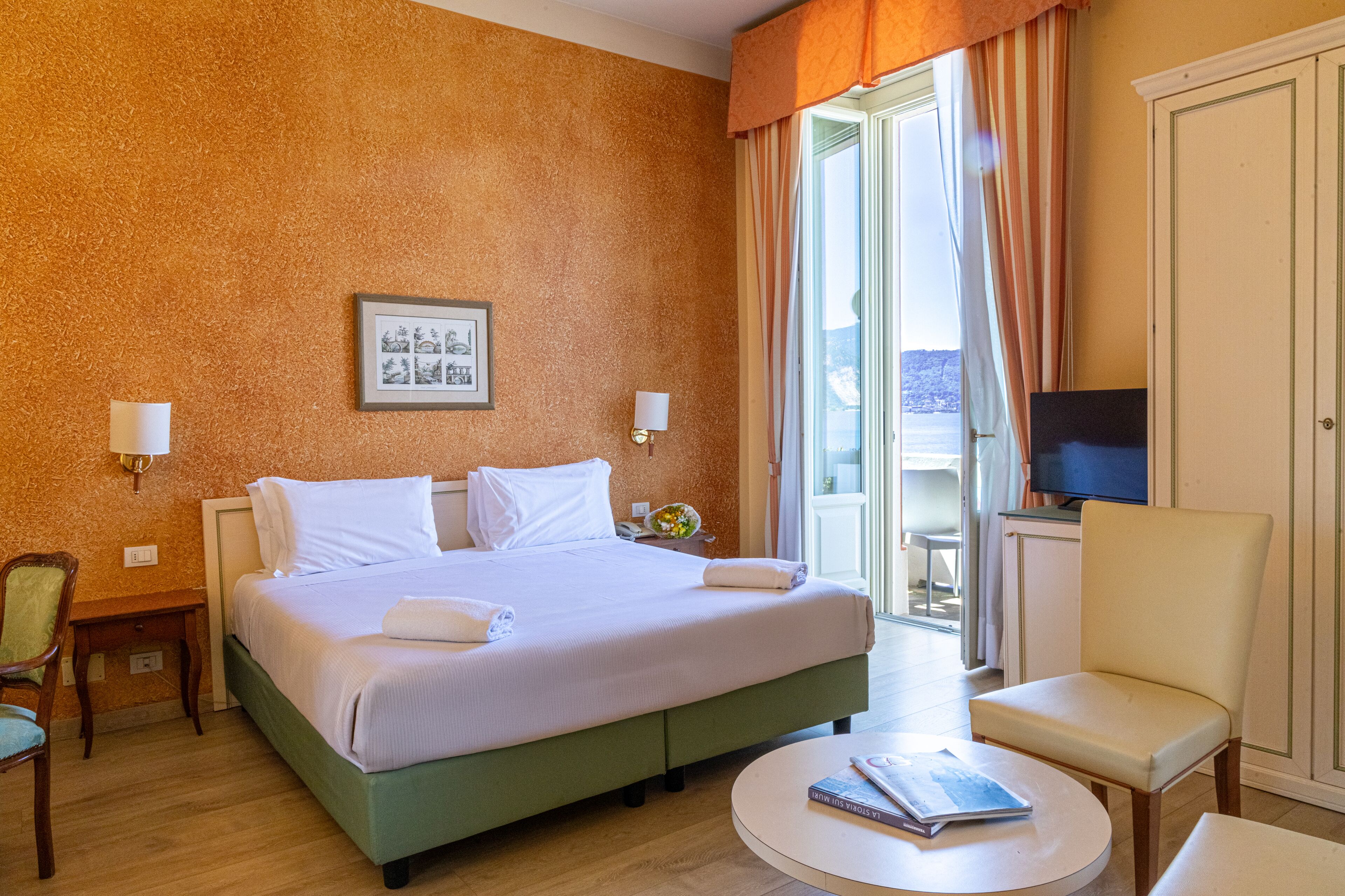 Una habitación de hotel con una cama grande, televisión, una silla y una mesita.