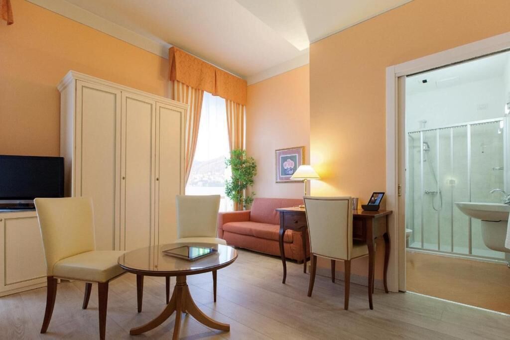 Sala de estar com sofá, cadeiras, mesa de centro, televisão e banheiro com pia e chuveiro.