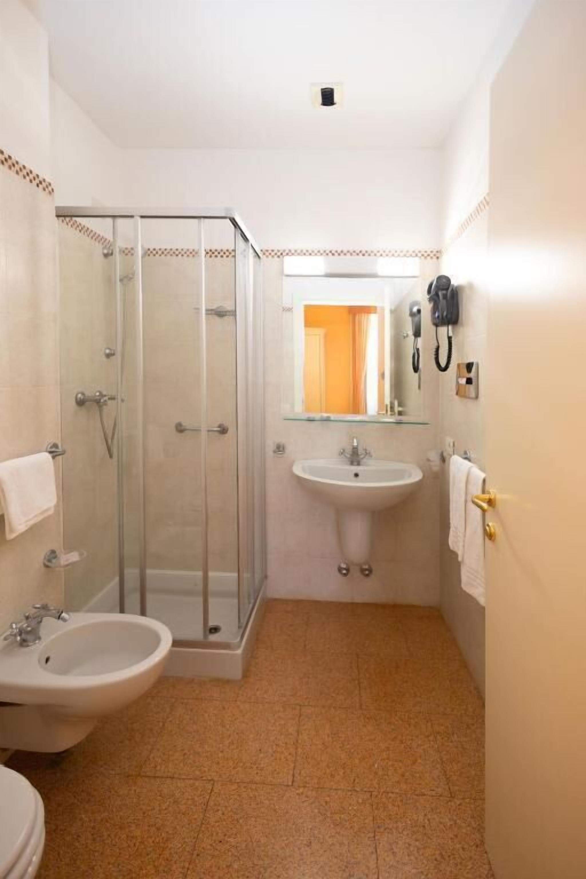 Un baño compacto con cabina de ducha de vidrio, lavamanos y bidé.